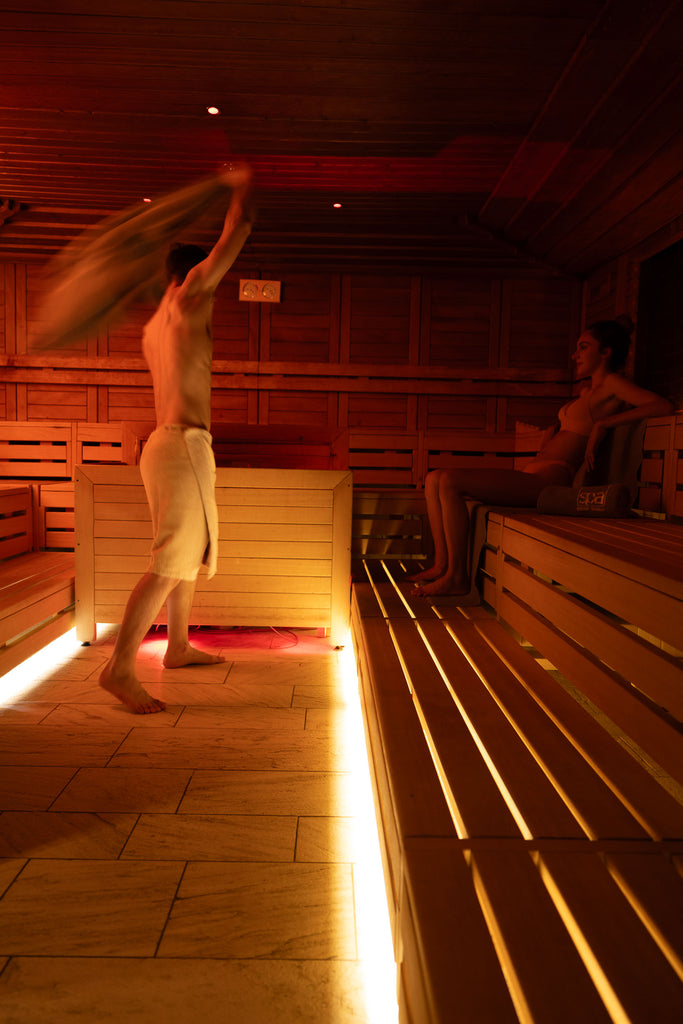 Maestro di sauna sventola un asciugamano durante un Aufguss. Modella cliente. Sauna di Bibione Thermae