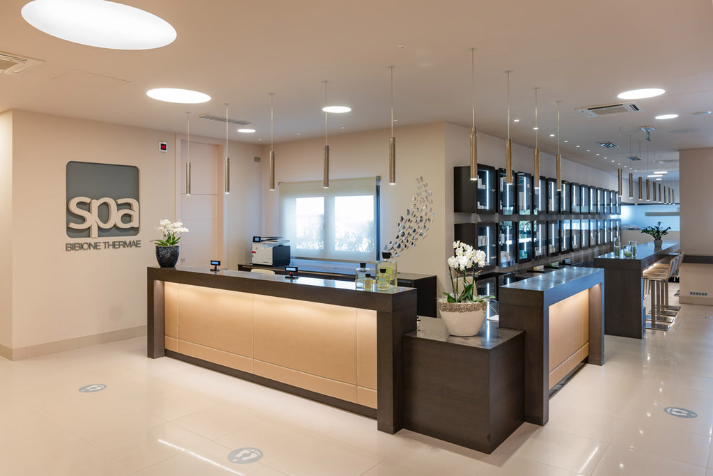 reception della SPA Beauty Farm delle terme di Bibione. Bancone e vetrine prodotti. Luci a cilindro sul soffitto